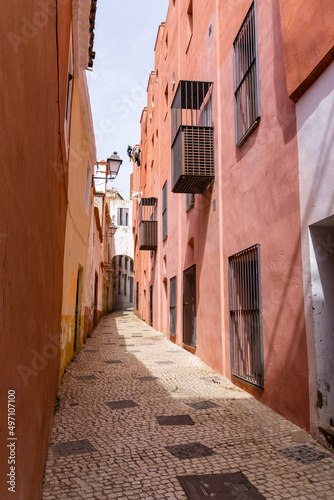 narrow pedestrian alley leading through tall colorful pink houses