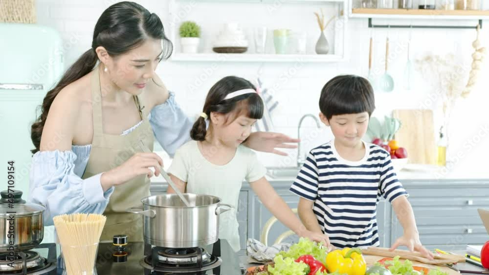 Happy Asian family making food together in kitchen at home. Enjoy family activity together. Happy Asian family making food together in kitchen at home. Enjoy family activity together.