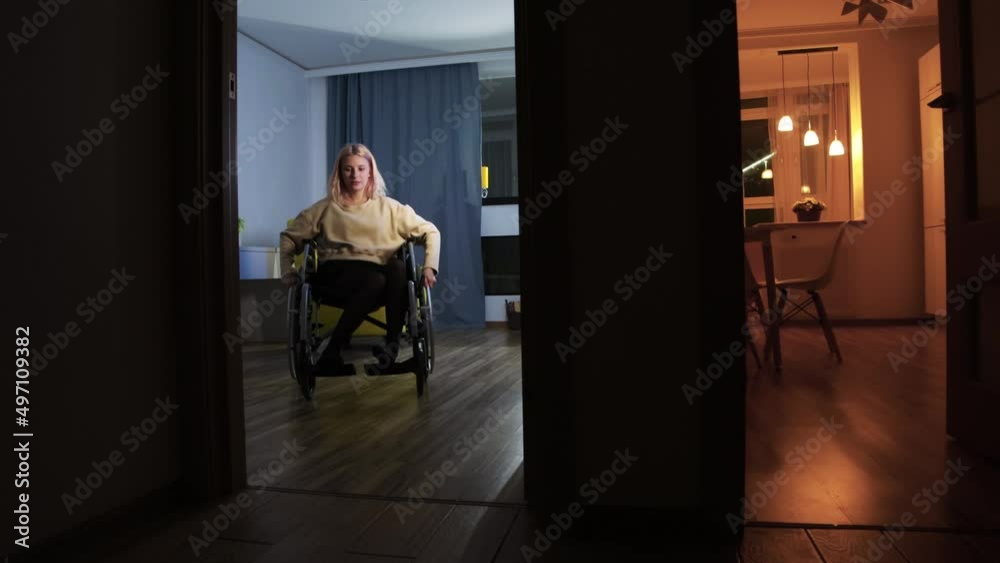 Young woman in a wheelchair going out of the living room Young woman in a wheelchair going out of the living room