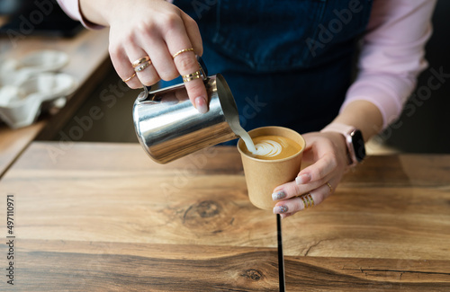 The process of making a barista cappuccino with a beautiful pattern on the foam in an eco-craft glass. Coffee to go concept.