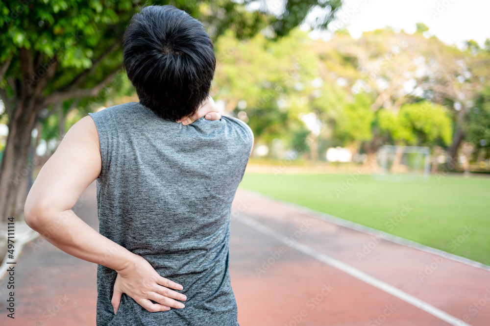 Spine pain. Man holding his neck and back which got injured during outdoor exercise in the park. Sport injury concept Spine pain. Man holding his neck and back which got injured during outdoor exercise in the park. Sport injury concept