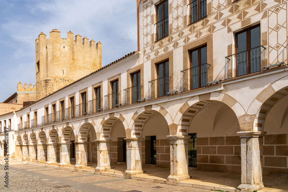arched portico and building of the University of Extremadura with the Alcazaba palace behind