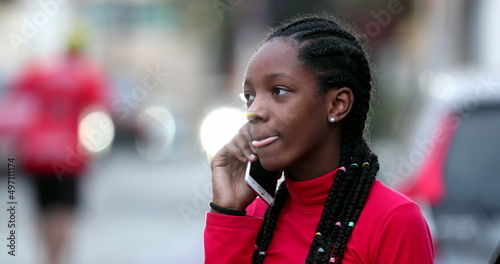 Young black teen girl talking on phone, candid african teenager discussing on cellphone