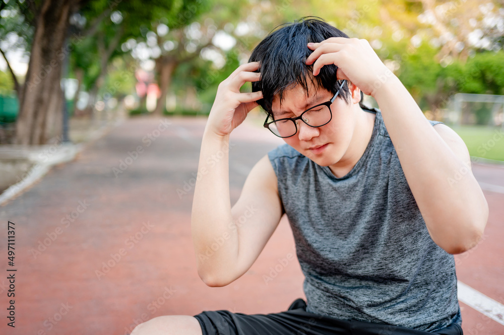 Asian man athlete feeling dizzy and tired while doing outdoor exercise in the park. Sport overtraining or Heat stroke concept Asian man athlete feeling dizzy and tired while doing outdoor exercise in the park. Sport overtraining or Heat stroke concept