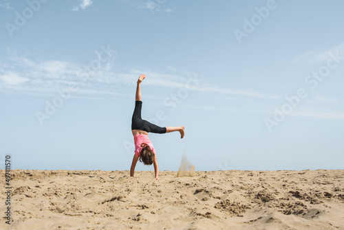 Girl doing a cartwheel in the sand on the beach