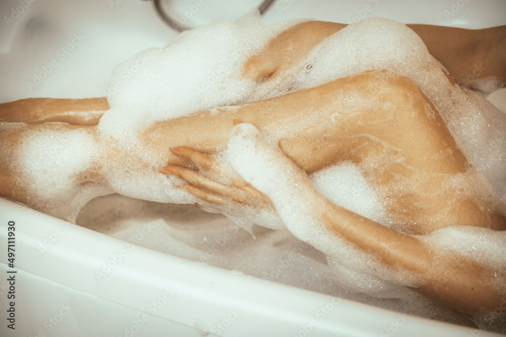 Fototapeta premium Women's feet in bath foam. View from above. Enjoy and relax in a spa hotel
