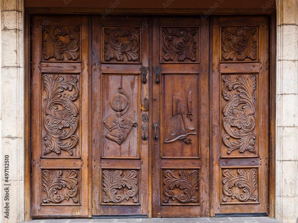 Horizontal view of old wooden door with carved floral motifs and books, globe and old fashioned feather writing pen, Quito, Ecuador