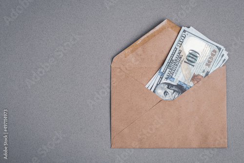 Dollar bills in a paper envelope on a gray background. Bonus, reward, benefits concept