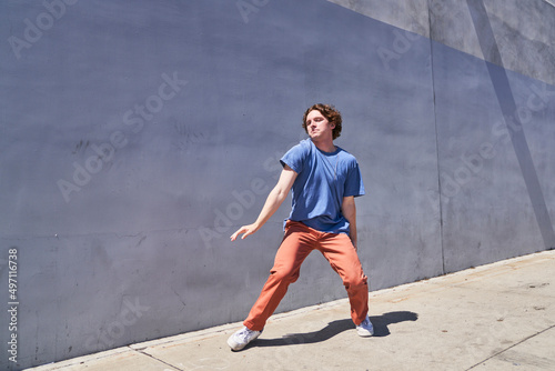 Man dancing with shoulders in front of gray blue wall 