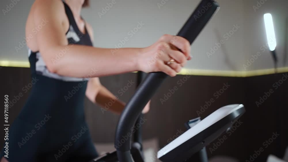 female running on elliptical orbitrek machine in fitness gym or apartment