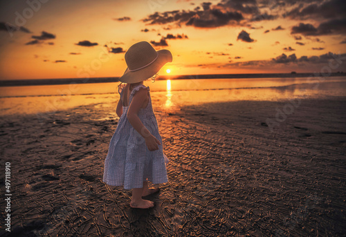little adorable girl 2 years joyfully on the beach in sunset on holiday