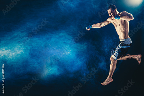 The professional athlete boxer in jump isolated on dsrk studio background. Fit muscular caucasian athlete fighting