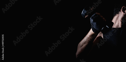 Young man practicing muscle and strength exercises with dumbbells. High intensity fitness. Copy space. Selective focus. © Rodrigo