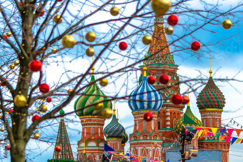 The domes of St. Basil's Cathedral on Red Square in Moscow against the background New Year's holiday toys in soft focus.