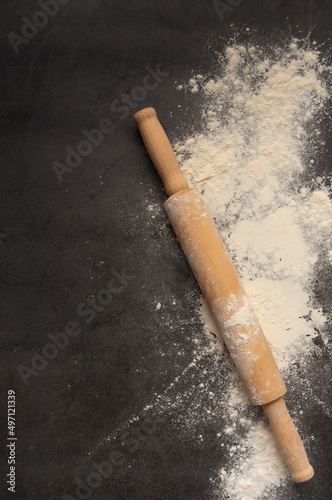 Baking background with the rolling pin with flour. On the dark table. Free space for text . Top view