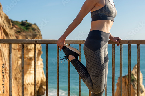 fit woman doing a quad stretch by the sea, close up