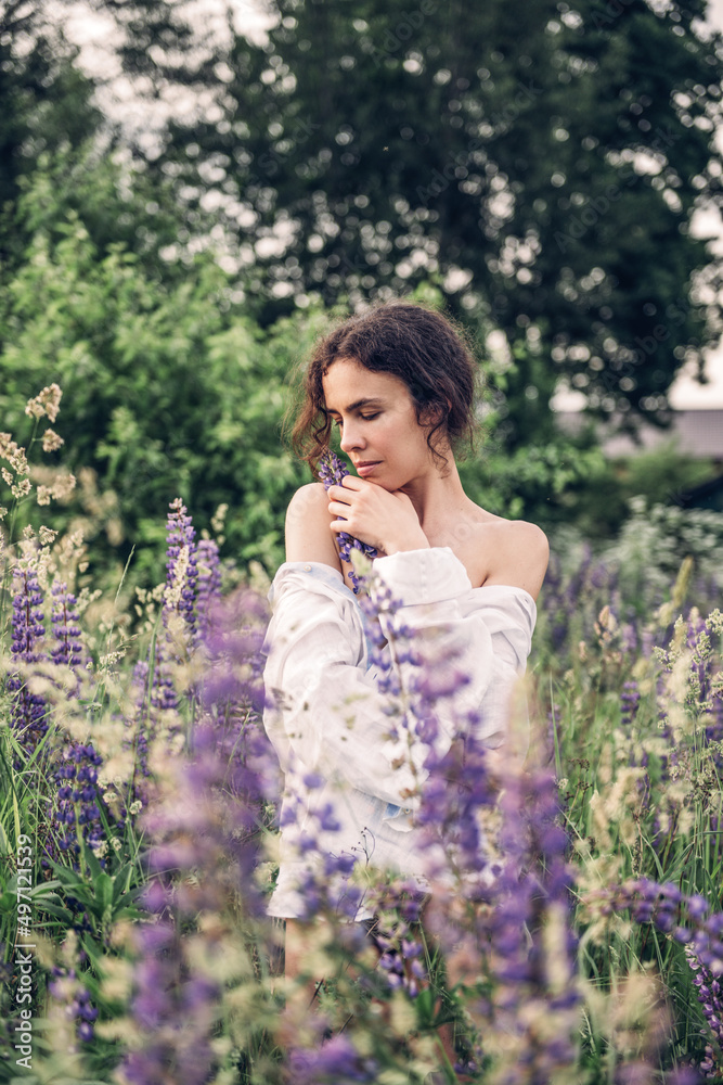 A beautiful woman dressed in a white linen shirt and hat walks in a field of blue and white flowers. Spring. Summer. In nature
A beautiful woman dressed in a white linen shirt and hat walks in a field of blue and white flowers. Spring. Summer. In nature