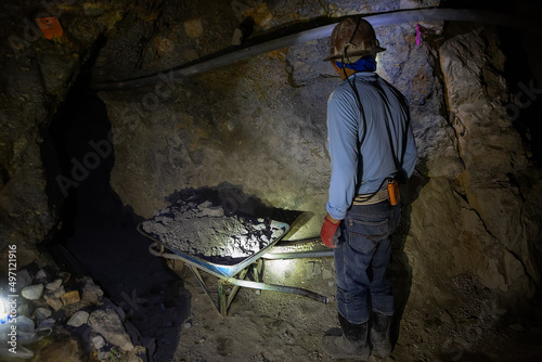 A miner in a protective helmet with a flashlight and a dot in the Potosi mine. Bolivia photo