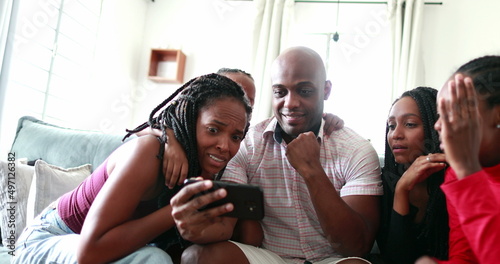 Family success victory reaction watching video on smartphone device. African black family cheering © Marco
