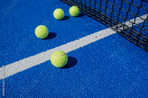 selective focus, four paddle tennis balls on a blue paddle tennis court close to the net © Vic