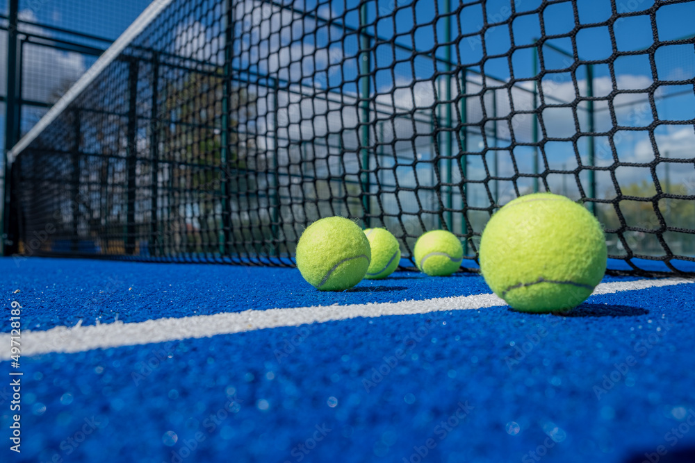 selective focus, four paddle tennis balls on a blue paddle tennis court close to the net