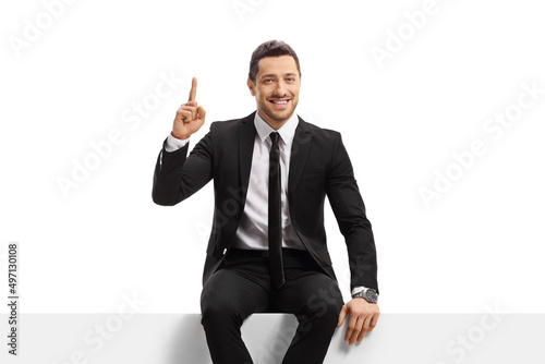 Businessman sitting on a blank panel and pointing up photo