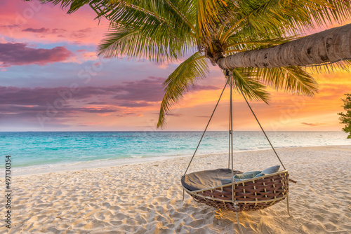 Tropical sunset beach and sky background as exotic summer landscape with beach swing or hammock and white sand and calm sea beach banner. Paradise island beach vacation or summer holiday destination  © icemanphotos