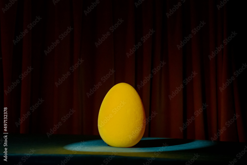 Yellow soft Easter egg on a table in dark Yellow soft Easter egg on a table in dark