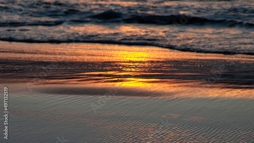 Sea waves and wet sand at sunset