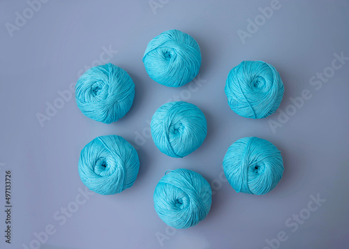 Seven balls of blue cotton yarn lie on a blue background