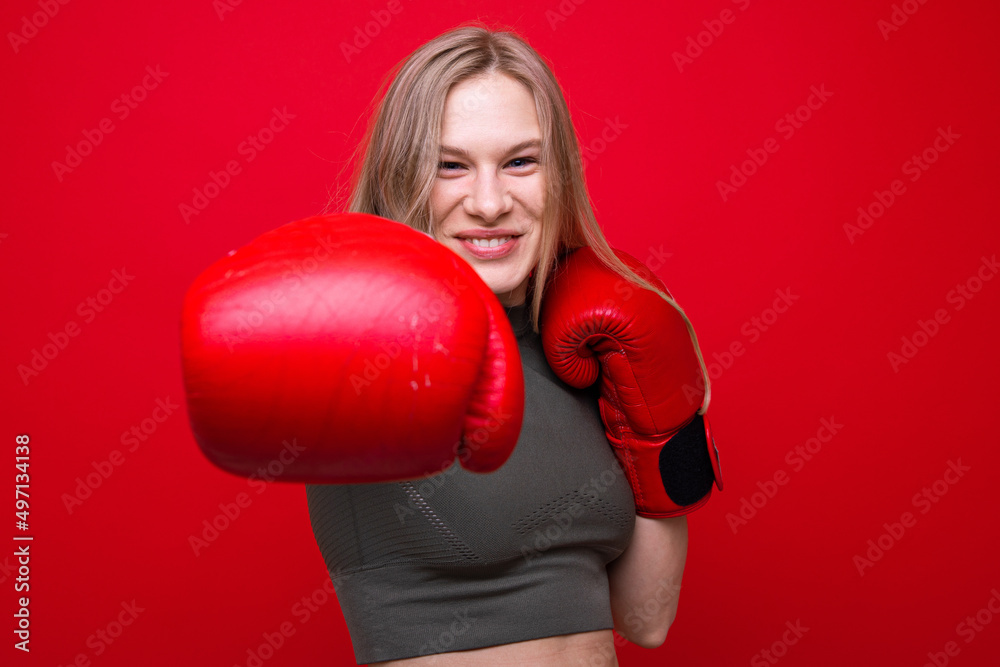 Sporty young woman in red boxing gloves is fooling around