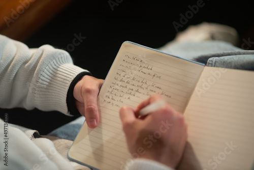 Close-up of young Caucasian man taking notes in notepad. Male student writing in notebook. Education concept photo