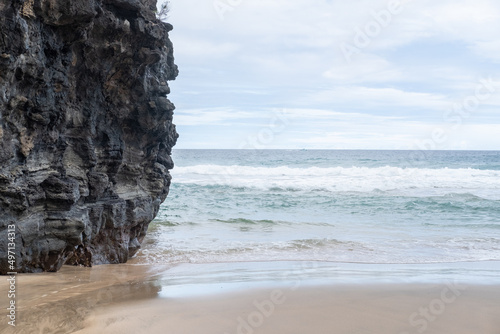 Lava rock wall with sand at base