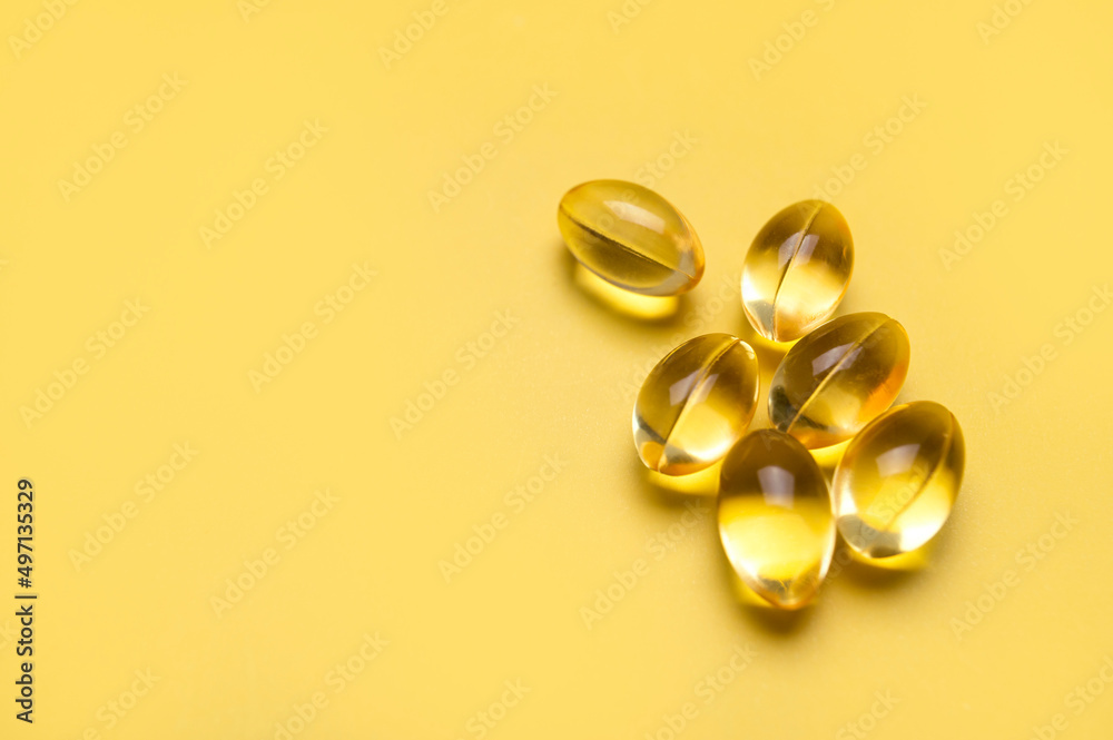 Capsules pill with vitamin D on yellow background close-up. Fish oil, Omega, Omega-3, dietary supplement, sunshine vitamin. Healthy lifestyle, medicine, cosmetology, diet. Pharmaceutical concept Capsules pill with vitamin D on yellow background close-up. Fish oil, Omega, Omega-3, dietary supplement, sunshine vitamin. Healthy lifestyle, medicine, cosmetology, diet. Pharmaceutical concept