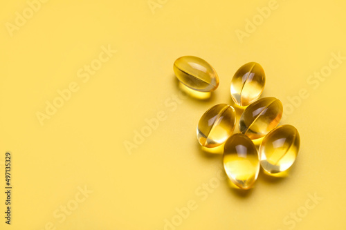 Capsules pill with vitamin D on yellow background close-up. Fish oil, Omega, Omega-3, dietary supplement, sunshine vitamin. Healthy lifestyle, medicine, cosmetology, diet. Pharmaceutical concept
