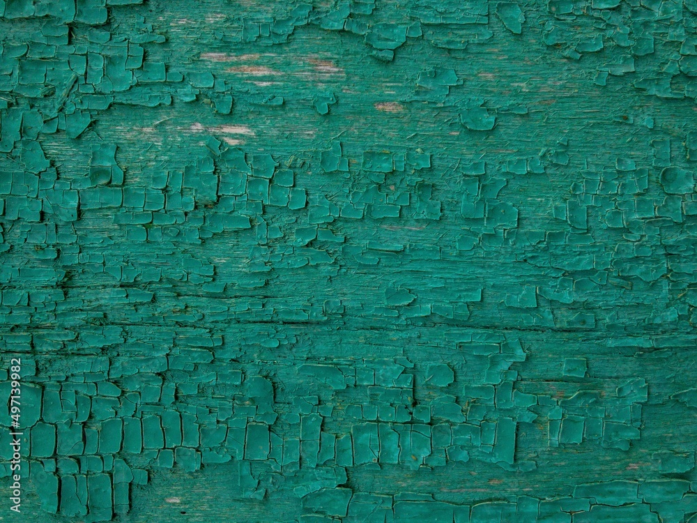 An old board made of natural wood, with cracked green paint on top.