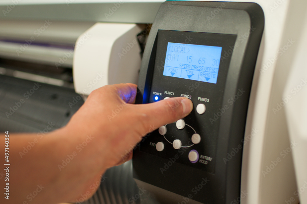 The printer operator presses the power button on the machine and starts printing. Man's hand and panel with buttons. The printer operator presses the power button on the machine and starts printing. Man's hand and panel with buttons.