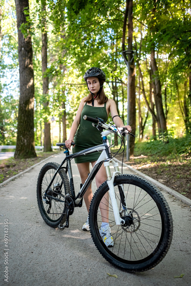 Pretty young slim woman on a bicycle rest after activity in the forest