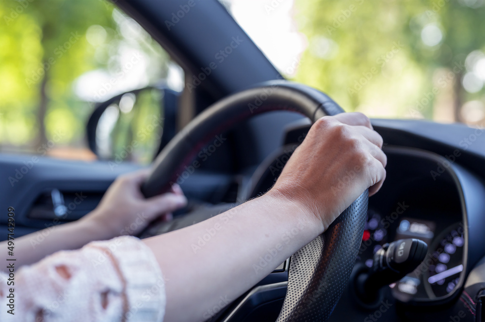 Close-up of female caucasian hands holding steering wheel. lady is sitting in a new car.