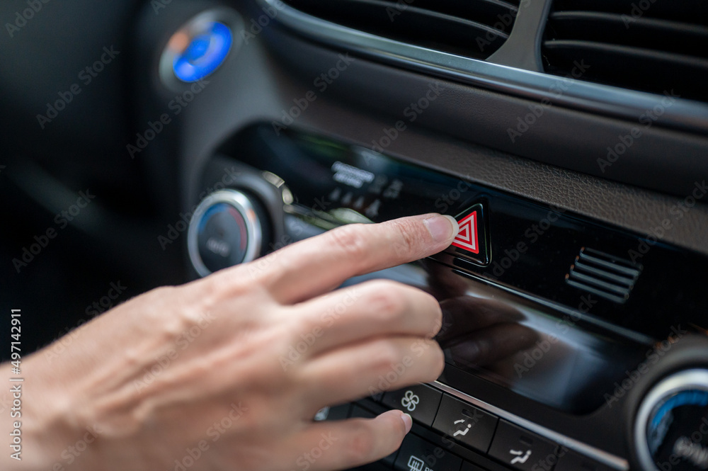 Close-up of a woman's hand pressing the emergency button in a new car.