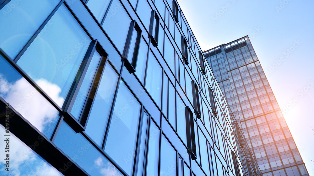 Obraz premium Modern office building with glass facade on a clear sky background. Abstract close up of the glass-clad facade of a modern building covered in reflective plate glass.