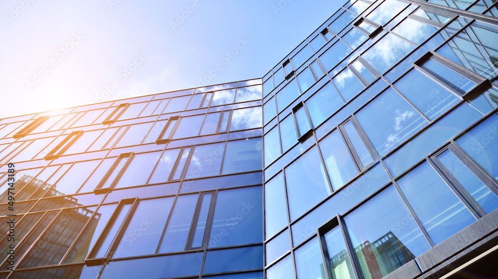 Modern office building with glass facade on a clear sky background. Abstract close up of the glass-clad facade of a modern building covered in reflective plate glass.