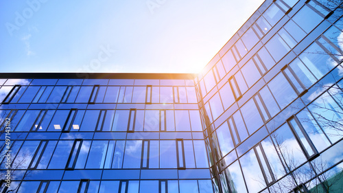 Modern office building with glass facade on a clear sky background. Abstract close up of the glass-clad facade of a modern building covered in reflective plate glass.