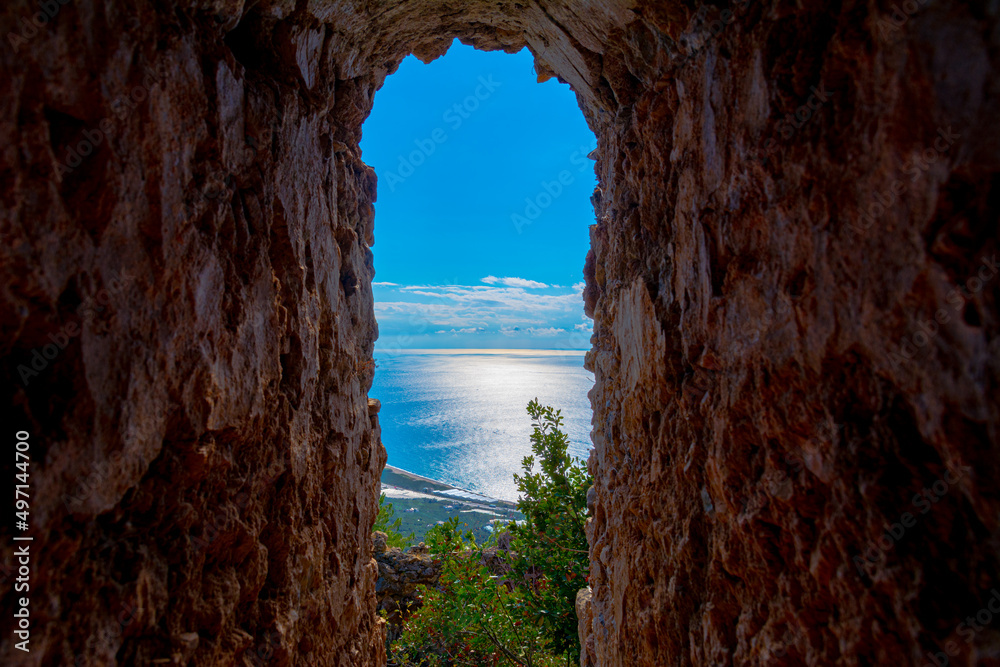 A window in an ancient building overlooking the sea.