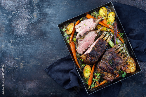 Traditional barbecue rack of lamb with carrot and potatoes served as top view on a rustic metal tray with copy space left
