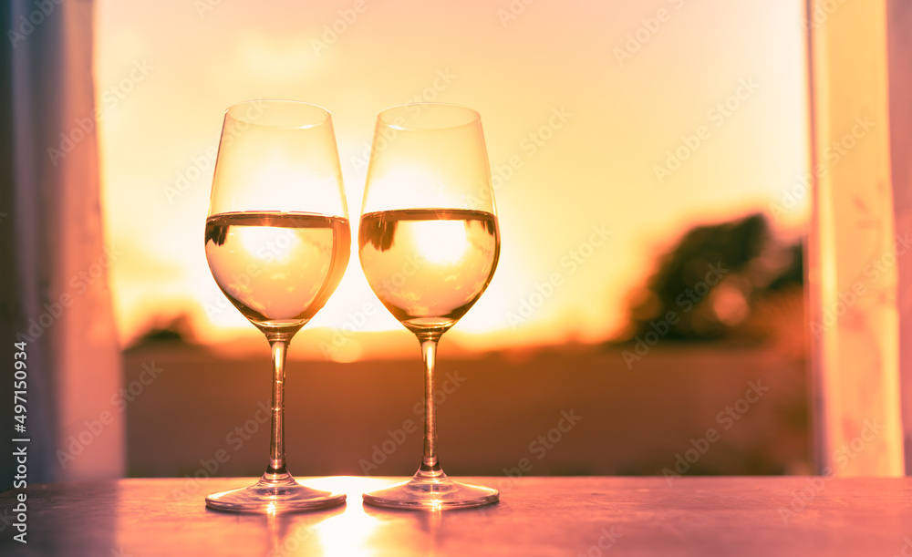 Pair of wine glasses on a bar at sunset 