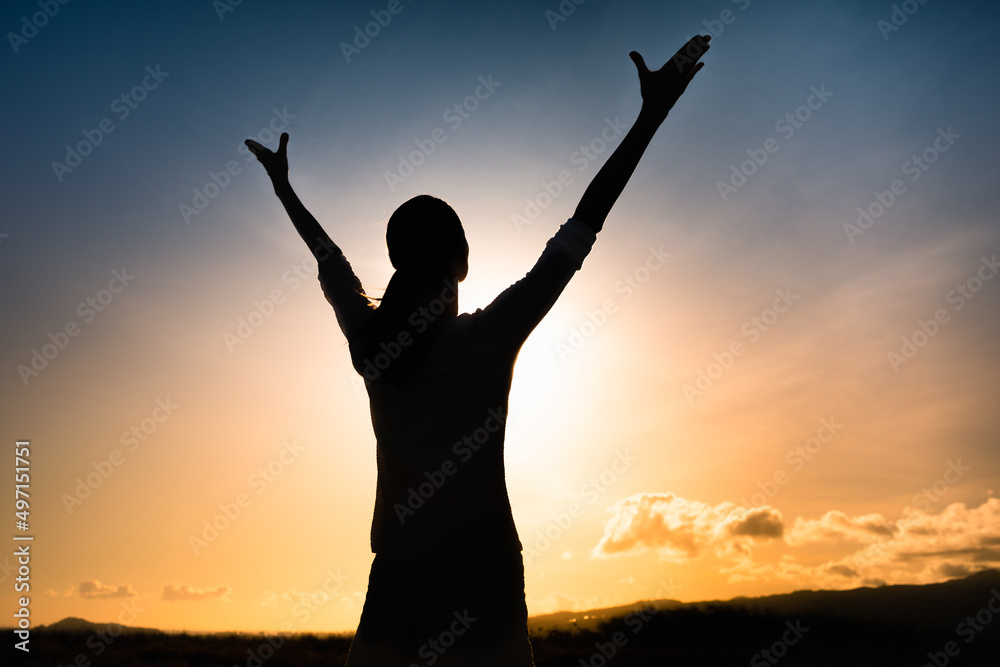 Happy woman with arms up to the sunrise feeling positive in a happy state of mind