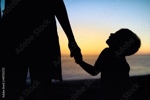 Child holding mothers hand looking up with trust. Children support and care concept 