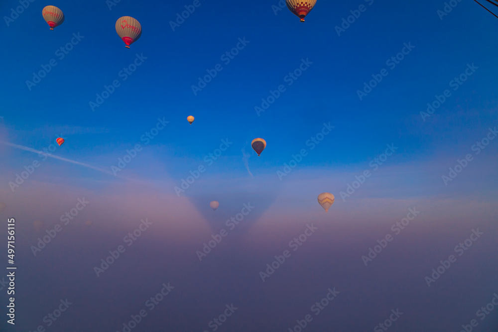 Hot air balloons flying over Cappadocia Goreme National Park Turkey with a view Erciyes mountain; foggy air