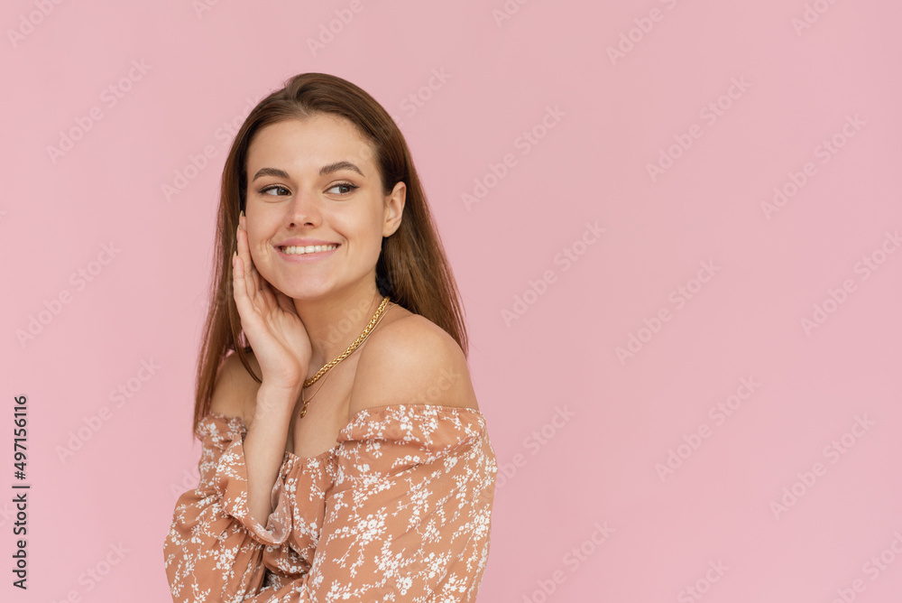 Obraz premium Pretty young woman in a beige dress on a pink background with copy space. Summer concept.